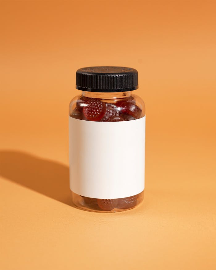A clear bottle filled with gummy vitamins on an orange background, ideal for health and wellness themes.